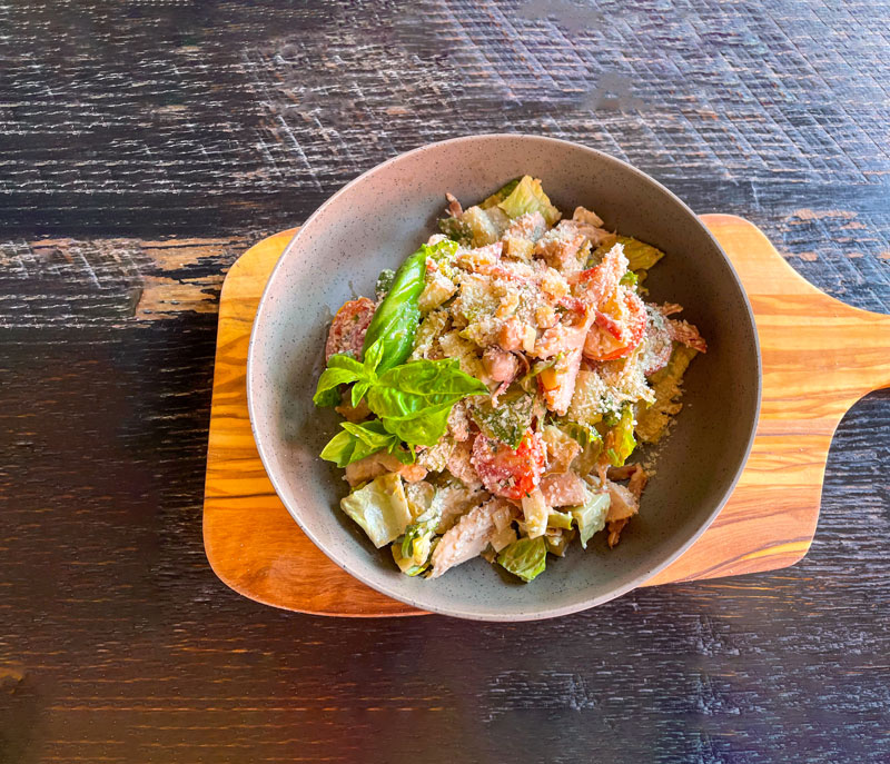 A chop chop salad plated on top of a wood cutting board